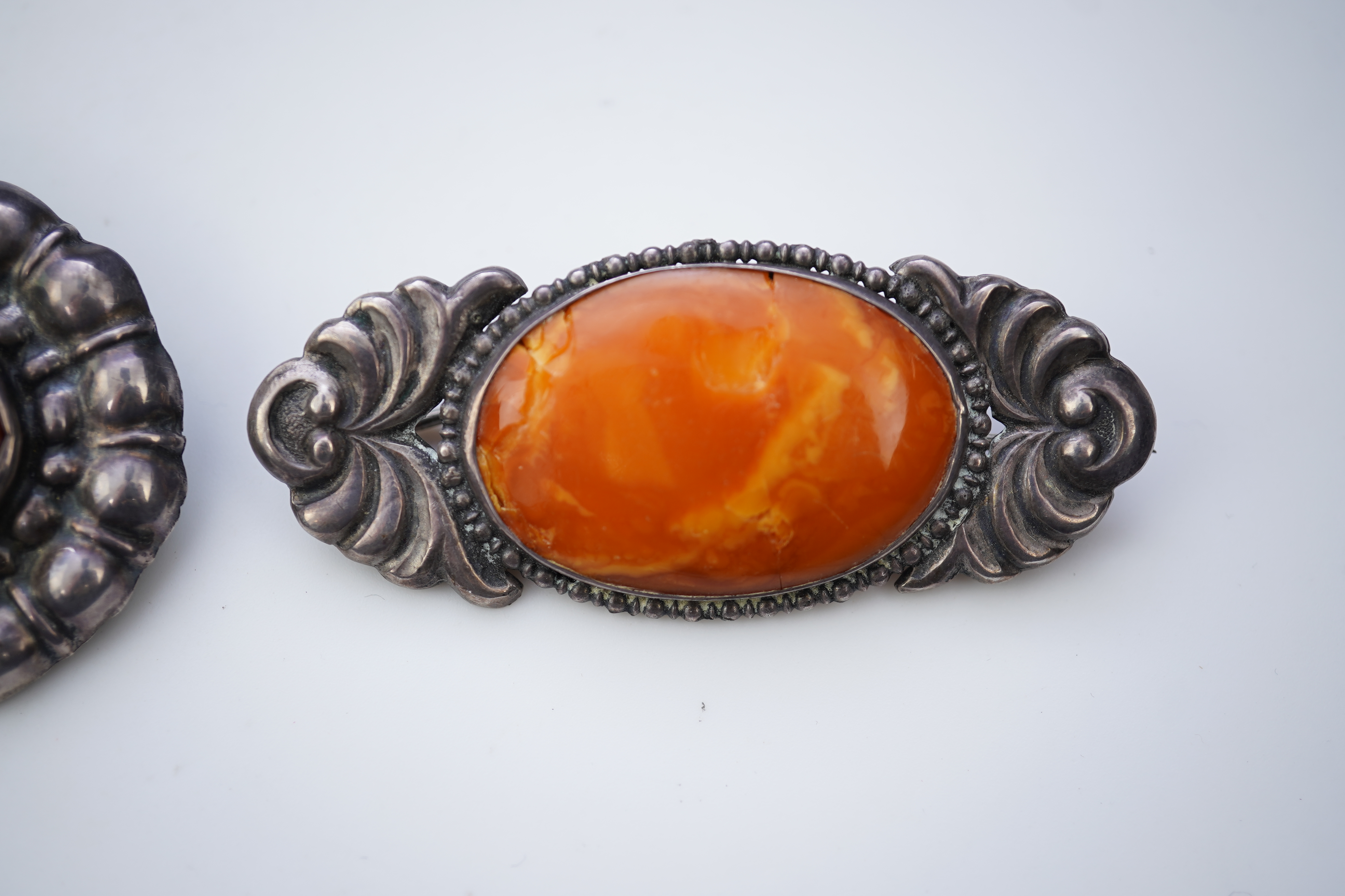 Three Arts & Crafts silver and amber brooches, early 20th century